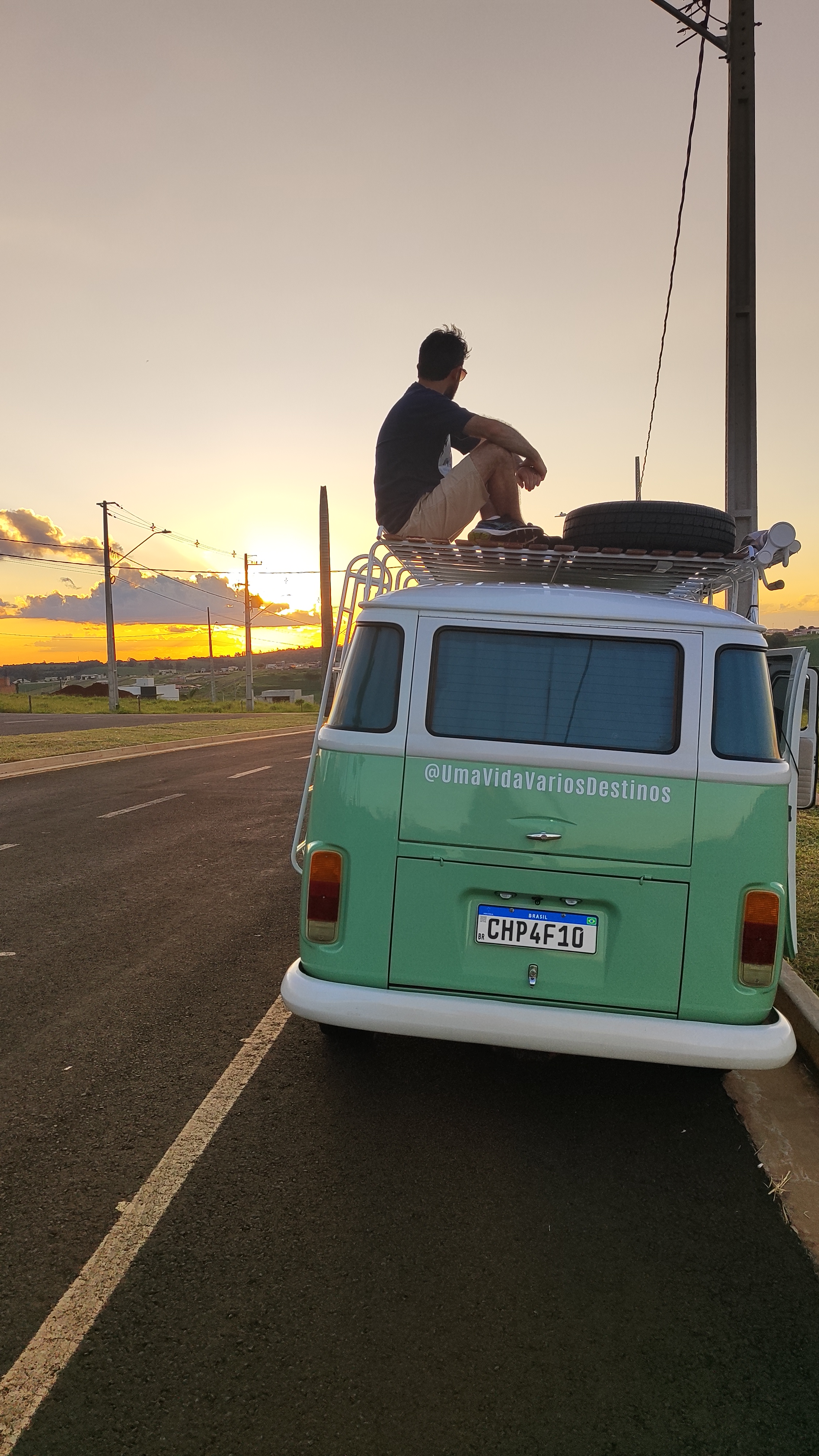 Kombi estacionada em frente a uma praia deserta ao pôr do sol
