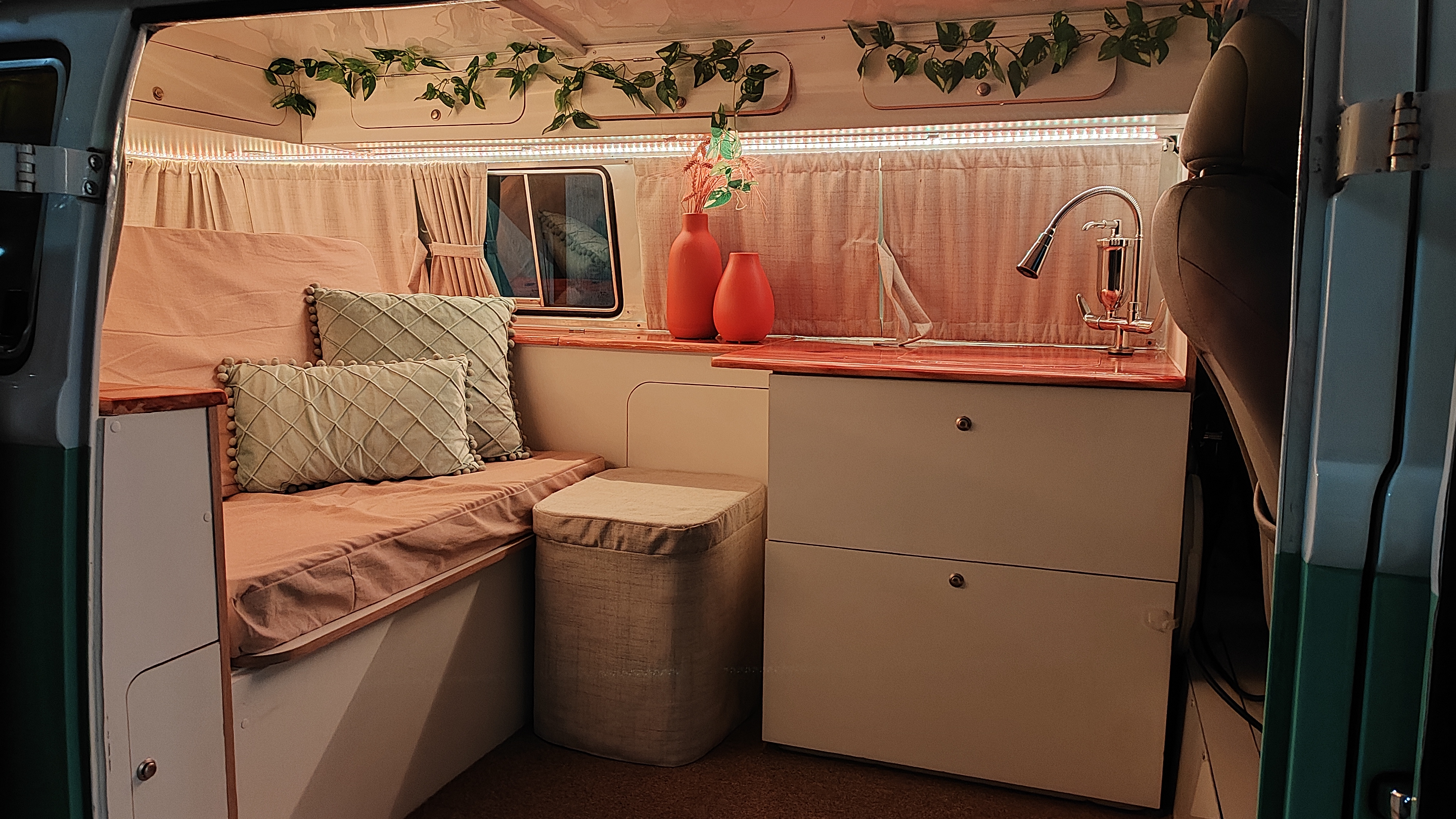 Interior da kombi adaptado para moradia, com detalhes em madeira e plantas